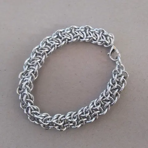 Bright silver aluminum chain mail bracelet on a grey background.