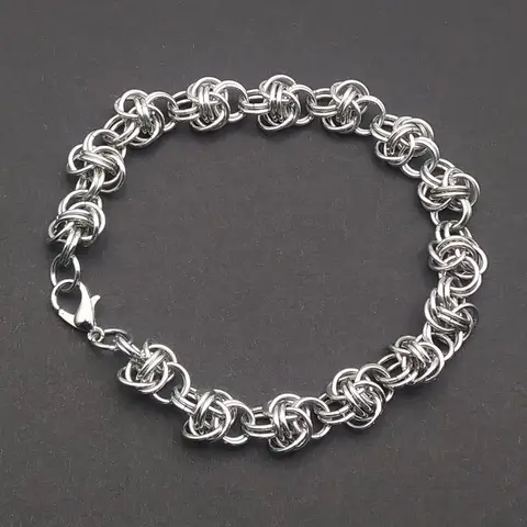 Bright silver aluminum chain mail bracelet on a dark grey background.