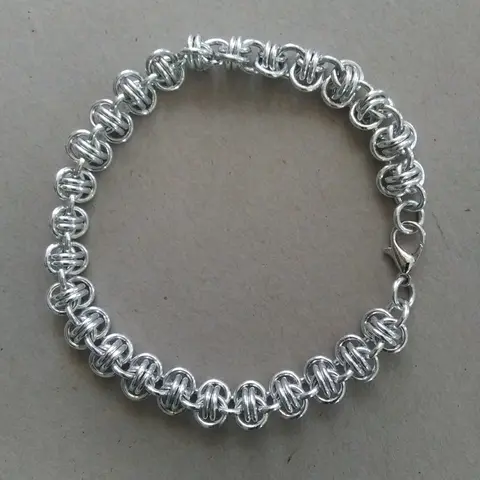 Bright silver aluminum chain mail bracelet on a grey background.