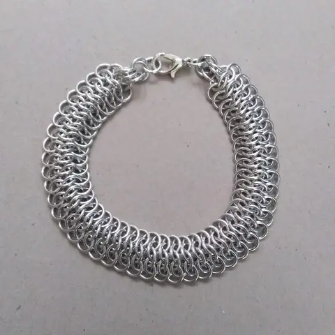 Bright silver aluminum chain mail bracelet on a grey background.