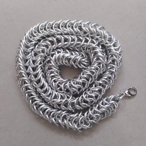 Bright silver aluminum chain mail necklace on a grey background.