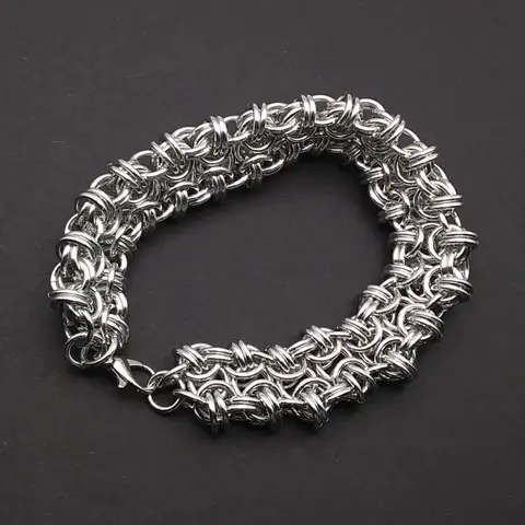 Bright silver aluminum chain mail bracelet on a dark grey background.