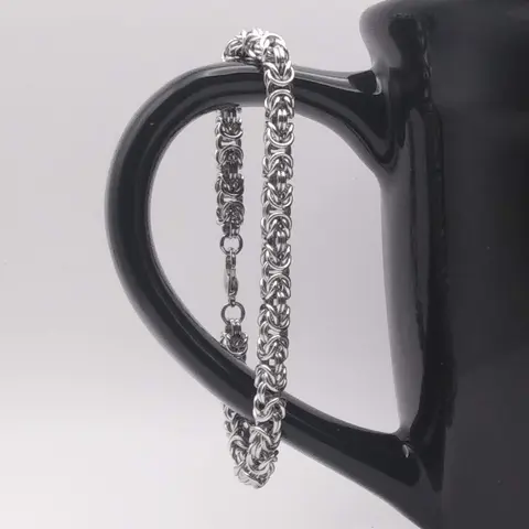 Bright silver aluminum chain mail bracelet on a black mug.