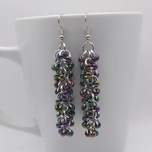 Bright silver aluminum chain mail earrings with dark rainbow beads on a white mug.