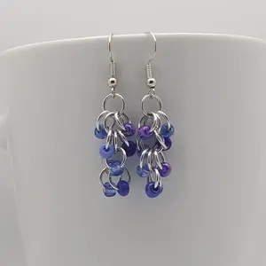 Bright silver aluminum chain mail earrings with sapphire mix beads on a white mug.