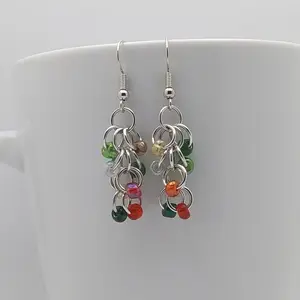 Bright silver aluminum chain mail earrings with holiday mix beads on a white mug.