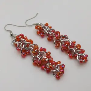 Bright silver aluminum long chain mail earrings with red rainbow beads on a white background.