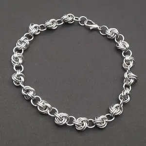 Bright silver aluminum chain mail bracelet on a dark grey background.