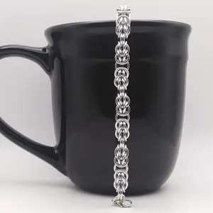 Bright silver aluminum chain mail bracelet on a black mug.