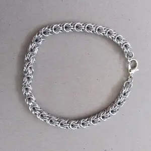 Bright silver aluminum chain mail bracelet on a grey background.