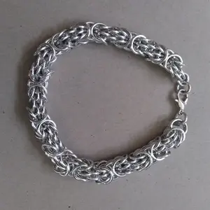 Bright silver aluminum chain mail bracelet on a grey background.