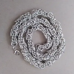 Bright silver aluminum chain mail necklace on a grey background.